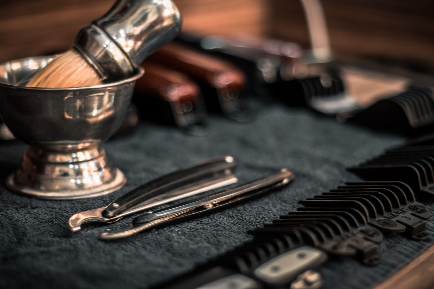 A shaving brush, bowl and straight razor laid out on dark cloth