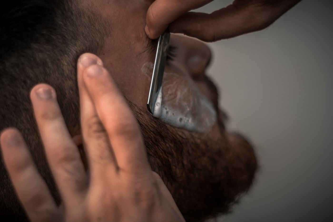 A straight razor drawn along a bearded jaw