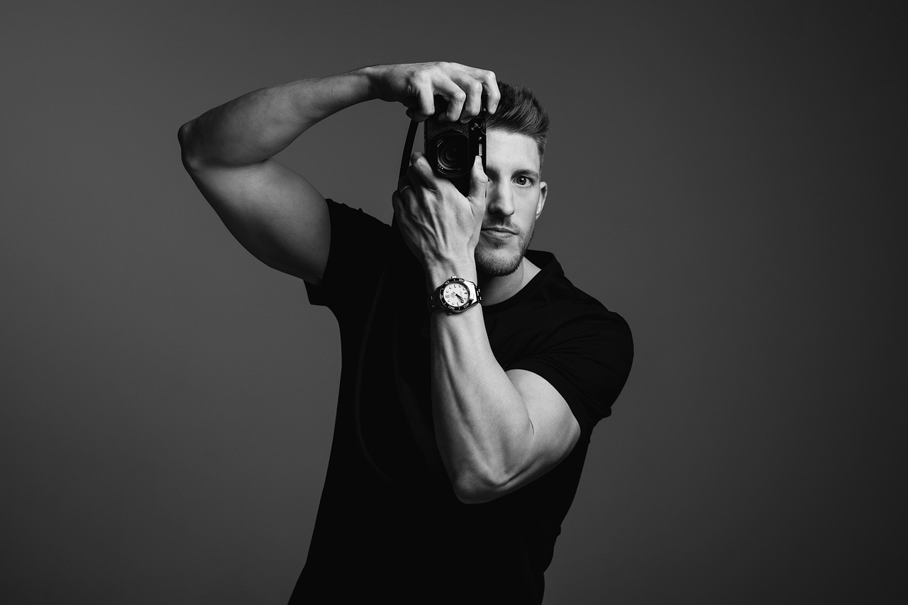 A photographer raising a camera to the eye, in monochrome