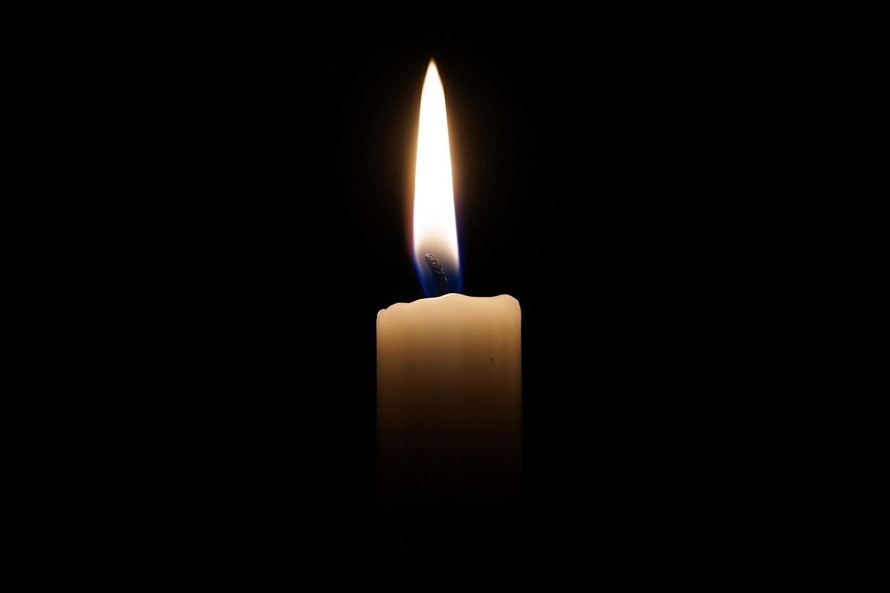 A single lit candle against pure darkness