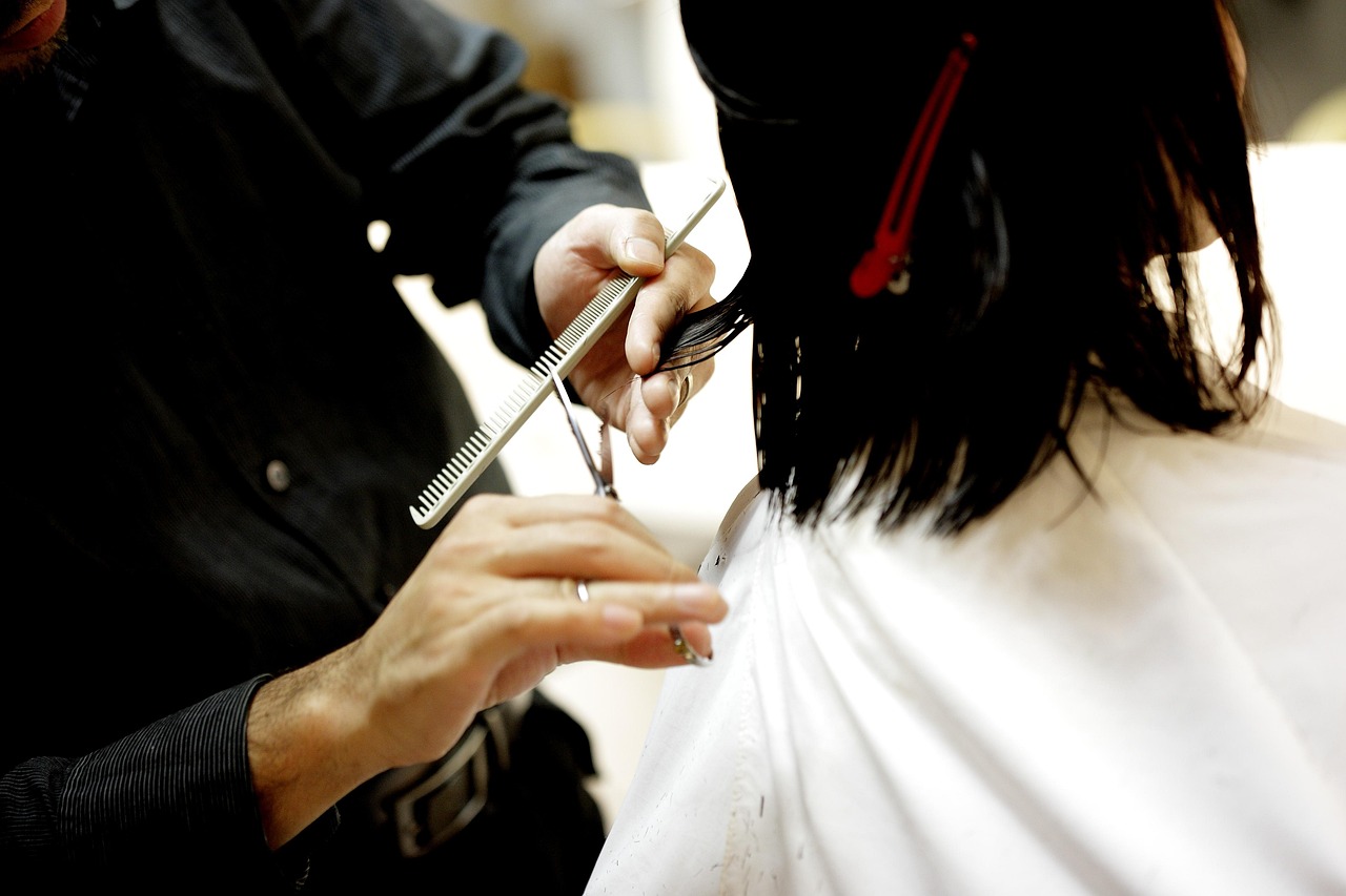 A stylist working scissors and comb through dark hair